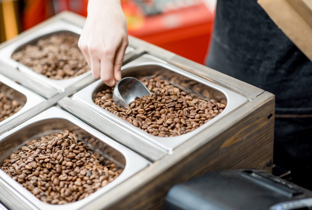 Handing scooping fresh coffee beans at a store.